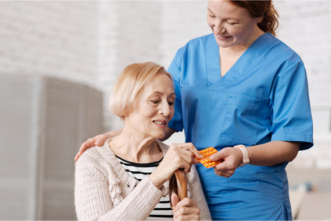 woman caregiver give medicine to elderly