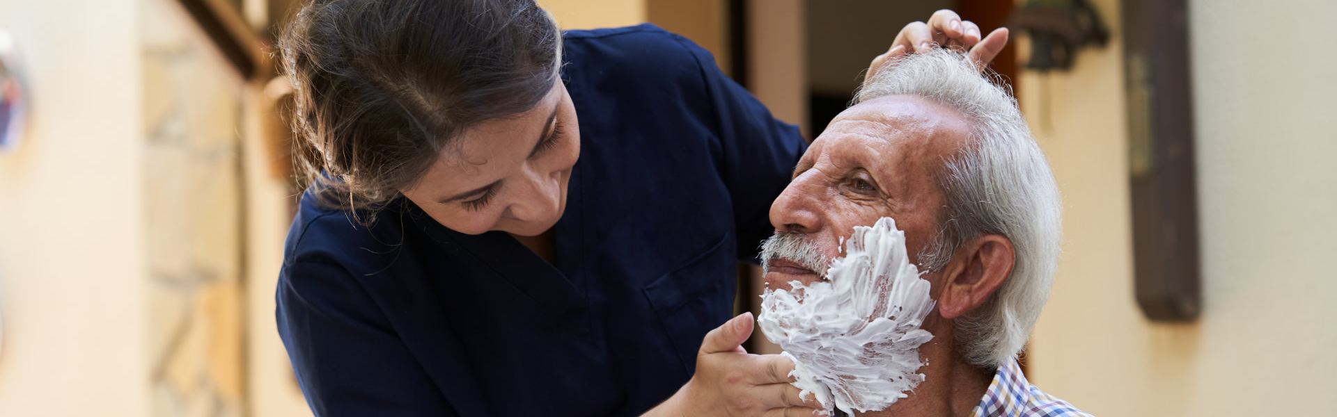 caregiver shaving the beard of an elderly